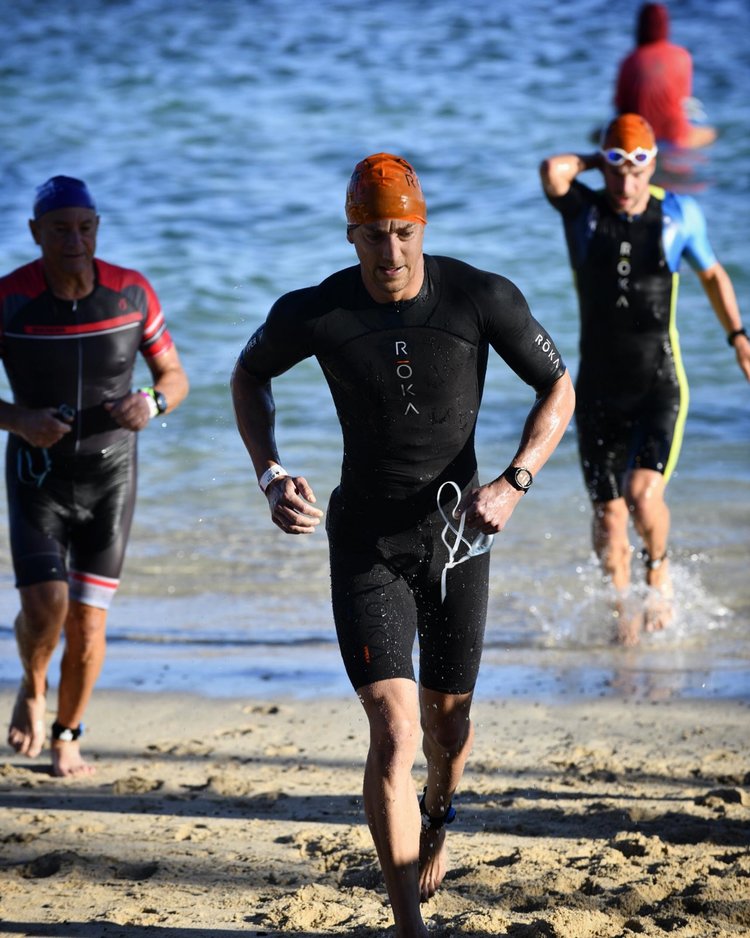 Coach Adam come up out of the water, from swimming, during a triathlon.