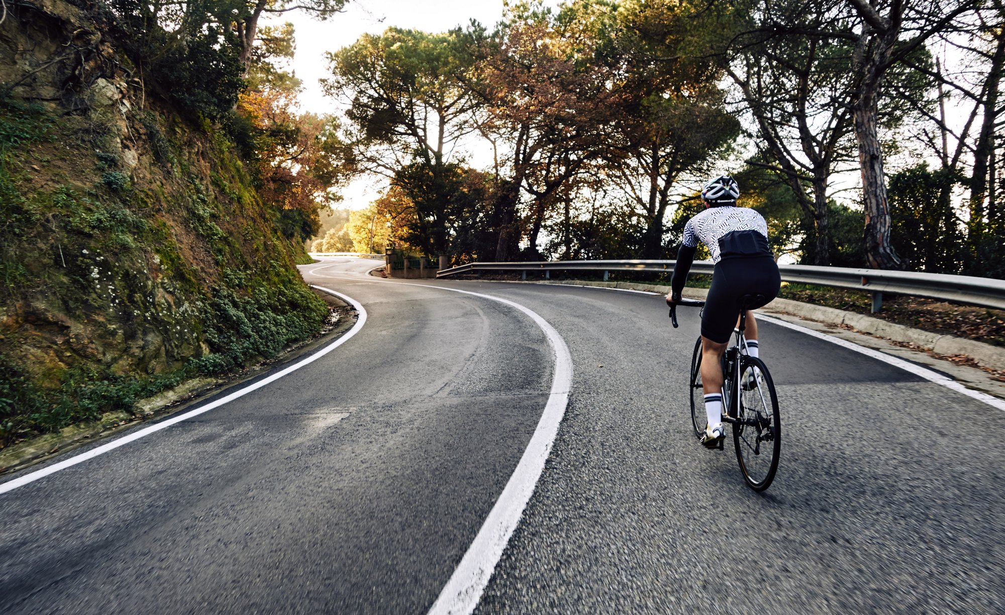 Cyclist climbing up a hill with their bike, being patient with the hill and remaining in their seat.